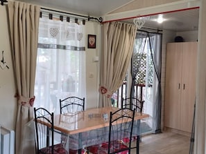 Un espace repas comprenant une table, des chaises et des rideaux.