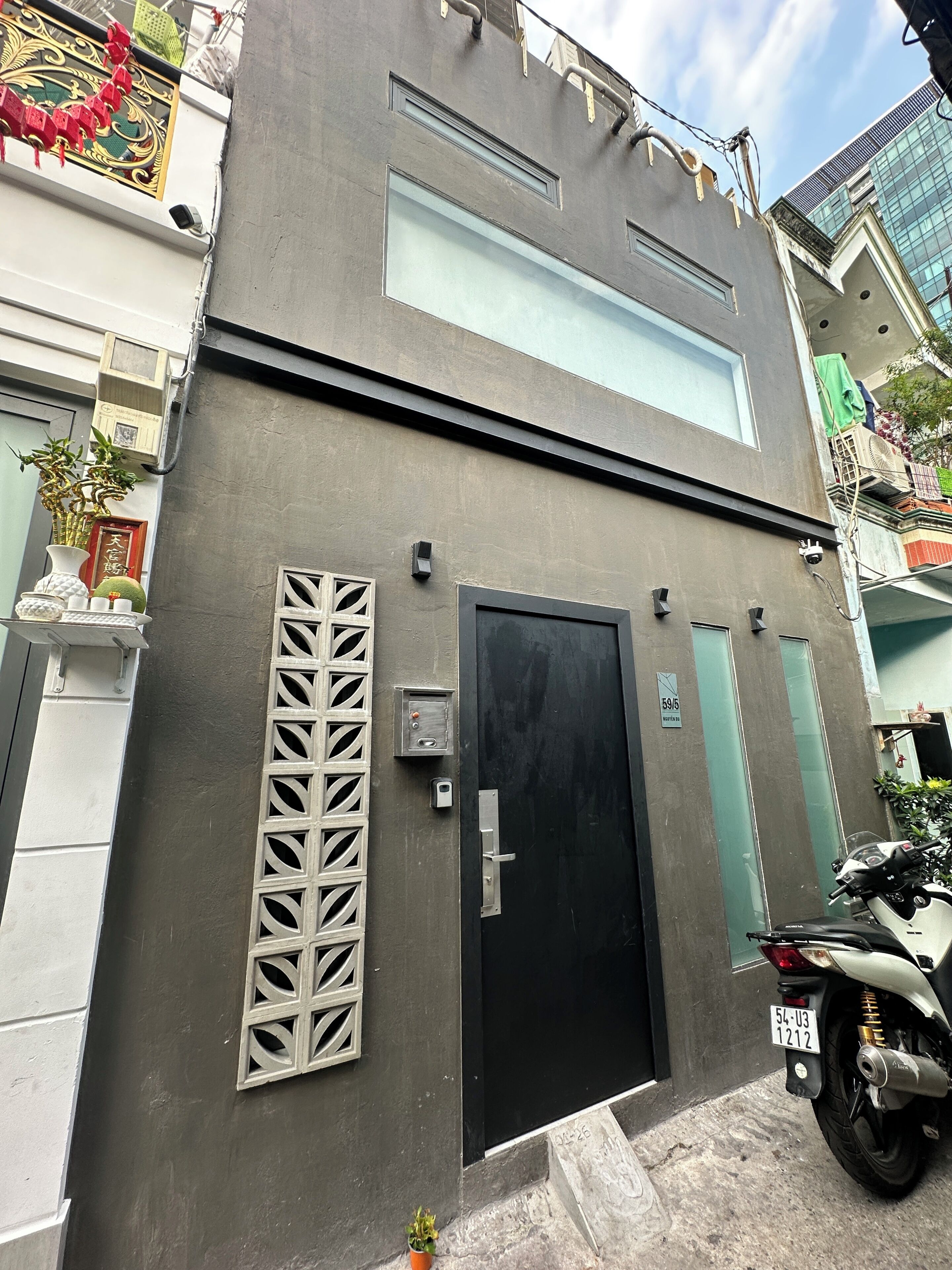 A modern building with a black door, a security camera, and a motorcycle parked outside.