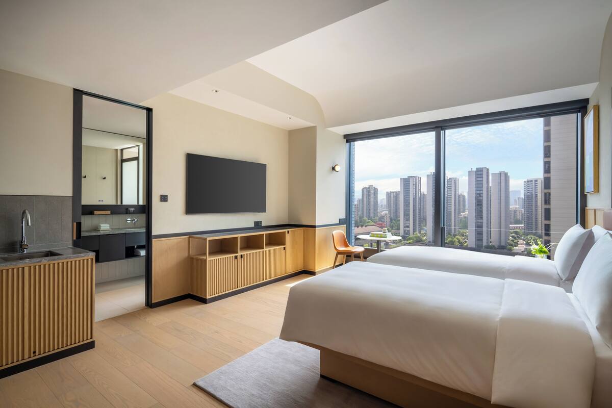 Habitación de hotel con una cama grande, televisión, vistas a la ciudad, kitchenette y baño.
