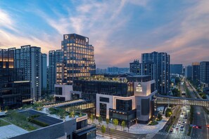 Un moderno complejo de edificios urbanos con varias torres altas, un llamativo frente de vidrio y una entrada bien iluminada.