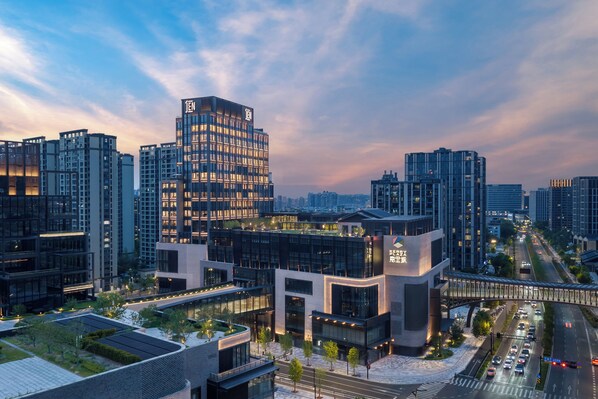 A modern urban building complex with multiple high-rise structures, a prominent glass facade, and a well-lit entrance. - Jen Hangzhou By Shangri-La (Hangzhou)