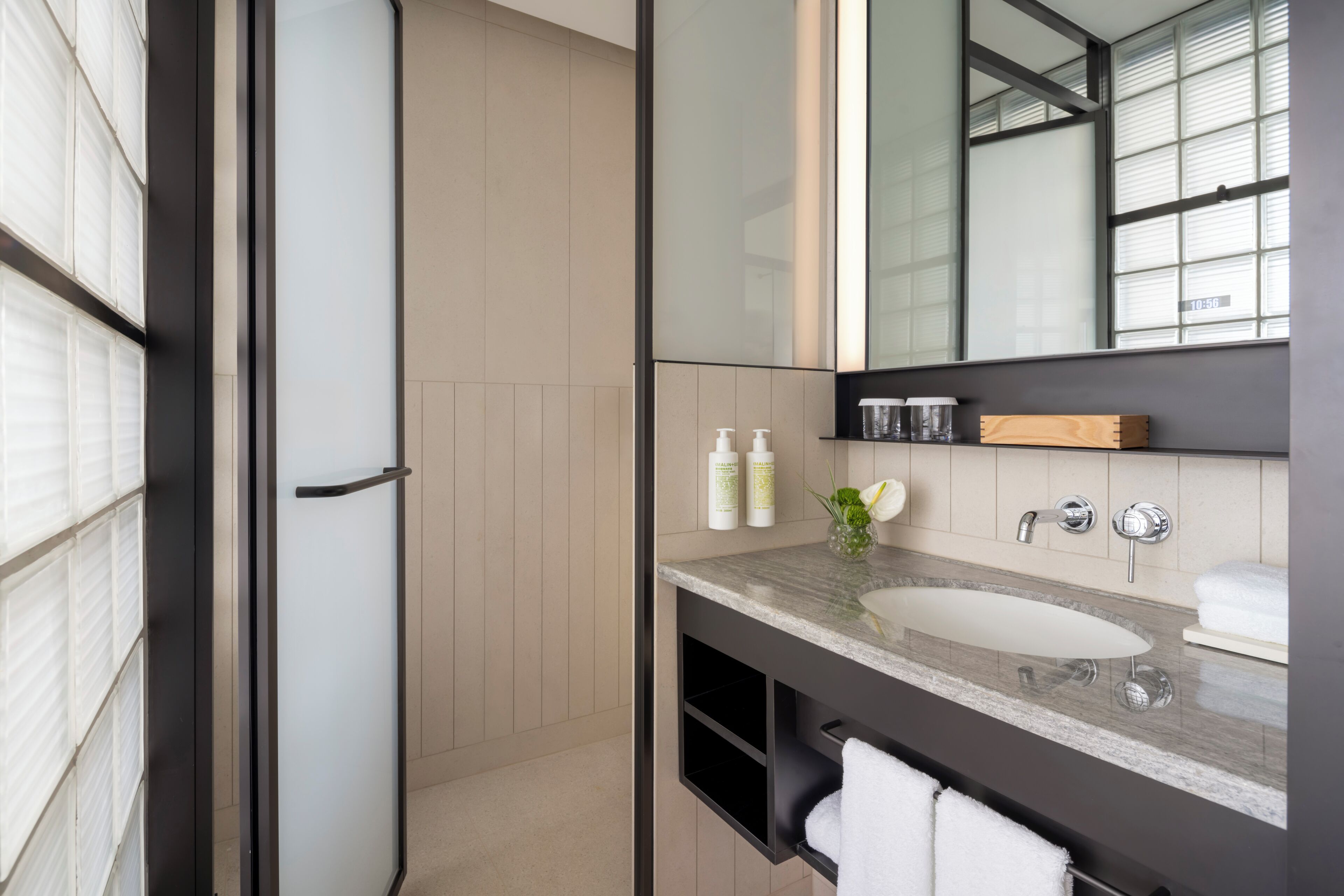 A modern bathroom with a large mirror, a sink, and a shower area.