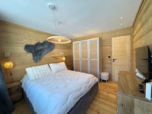 Ein Schlafzimmer mit einem Bett, einem Kleiderschrank, einem Fernseher und einer Wandleuchte.