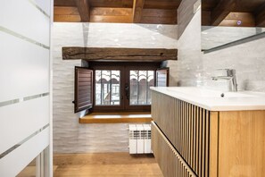 A bathroom with a wooden bench, a sink, and a window with shutters. - Villa Camila - El Pajar (Villarraba)