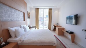 Una habitación de hotel moderna con una cama grande, un escritorio, una televisión y vistas al exterior.