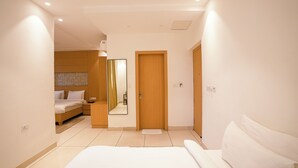Una habitación de hotel moderna con una cama grande, una puerta de madera y una mesita de noche pequeña.