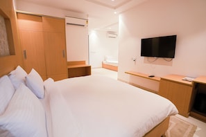 A bedroom with a bed, a TV, a wardrobe, and a desk. - Annekaa Heights (Vrindavan)