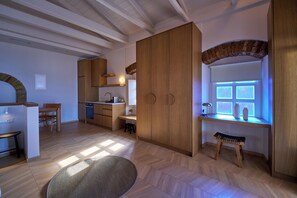 A modern kitchen with wooden cabinets, a dining area with a bench, and a window with natural light. - 1-bedroom apartment in the heart of Parga (Parga)