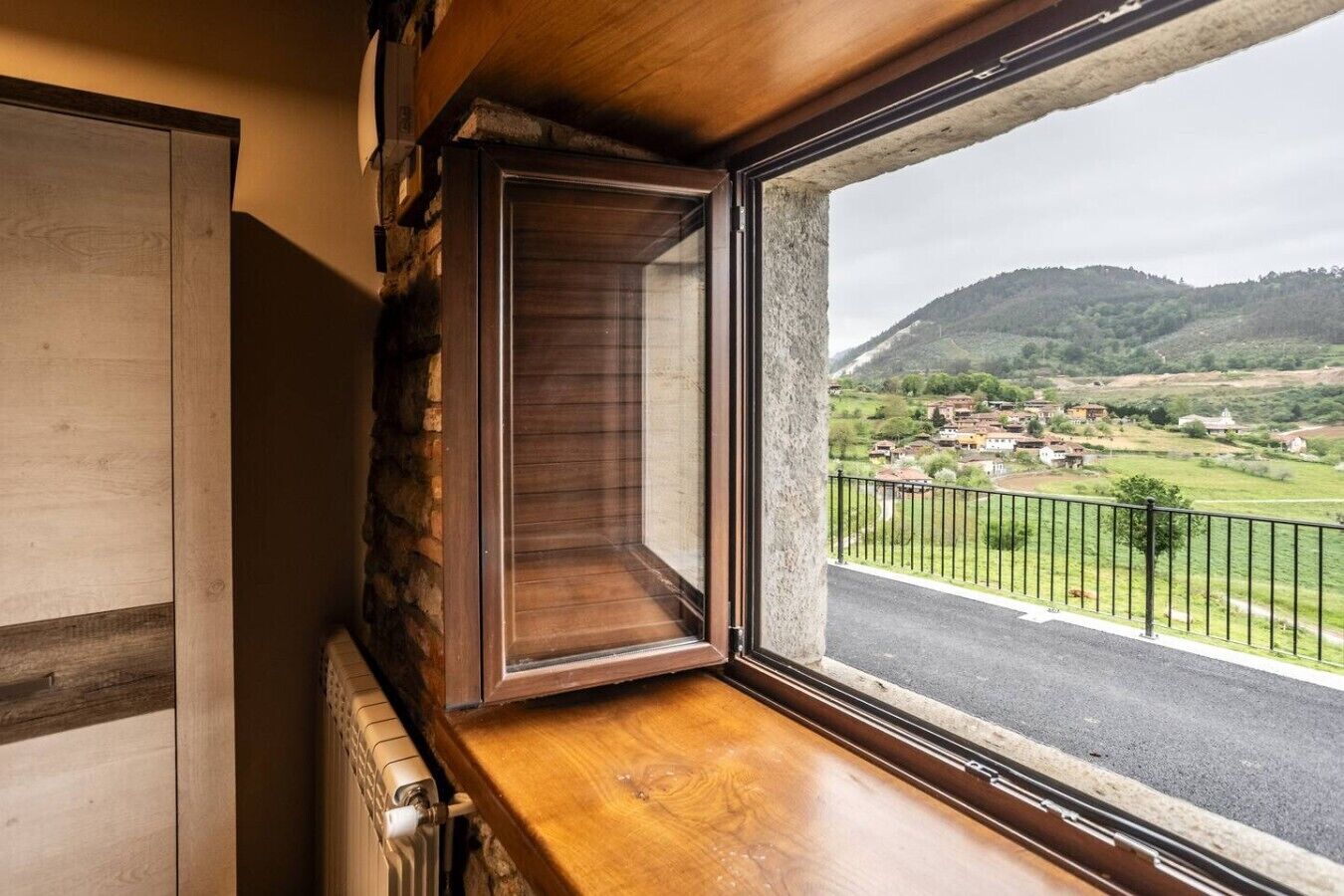 Un rincón de una habitación con una ventana que da a un paisaje rural.