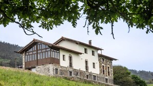 A two-story house with a stone base and a white upper level, large windows, and a sloped roof. - Villa Camila - El llagar (Villarraba)