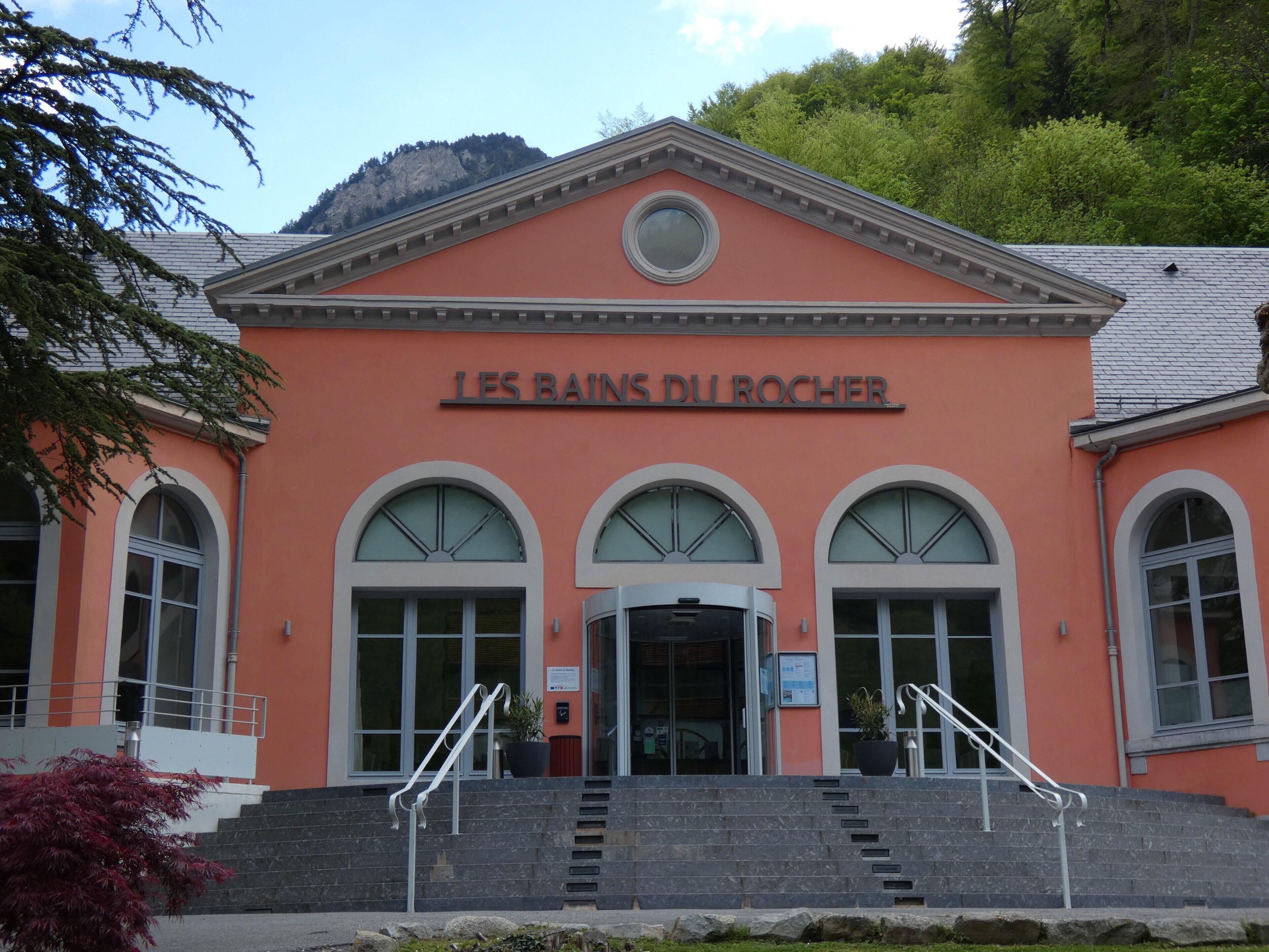 Un edificio con ventanas arqueadas y un letrero que dice 'LES BAINS DU ROCHER'.
