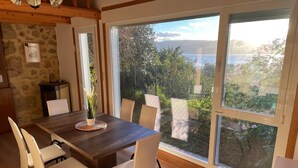Comedor con una mesa grande, sillas y vista a un lago y árboles.