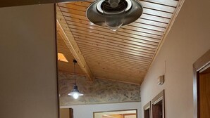 Un pasillo con techo de madera, piso de baldosas y puertas que dan a otras habitaciones.