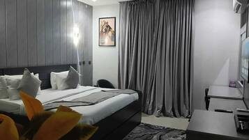 Een moderne hotelkamer met een bed, een bureau, een stoel, een televisie en een schilderij aan de muur.