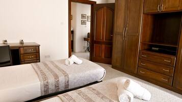 Habitación de hotel con dos camas, armario de madera y un escritorio.
