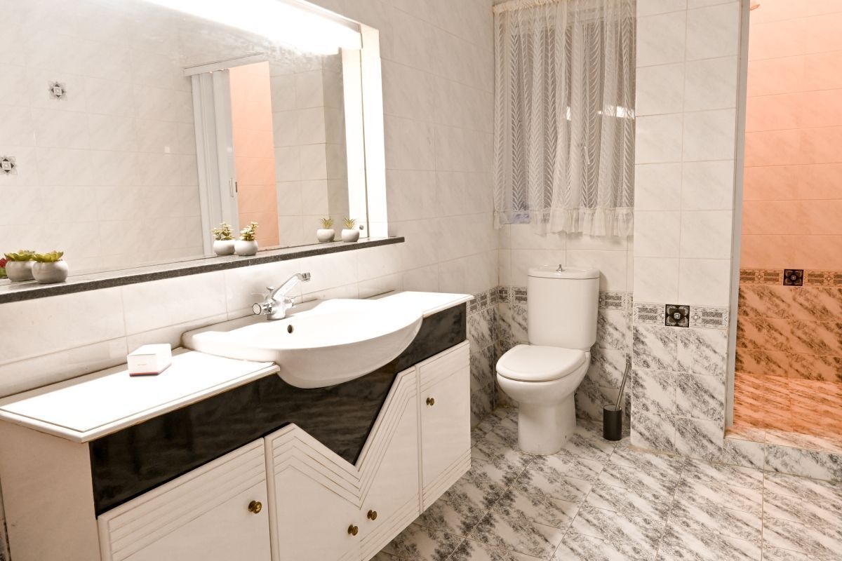 Een moderne badkamer met een wit wastafelmeubel, wastafel en toilet.