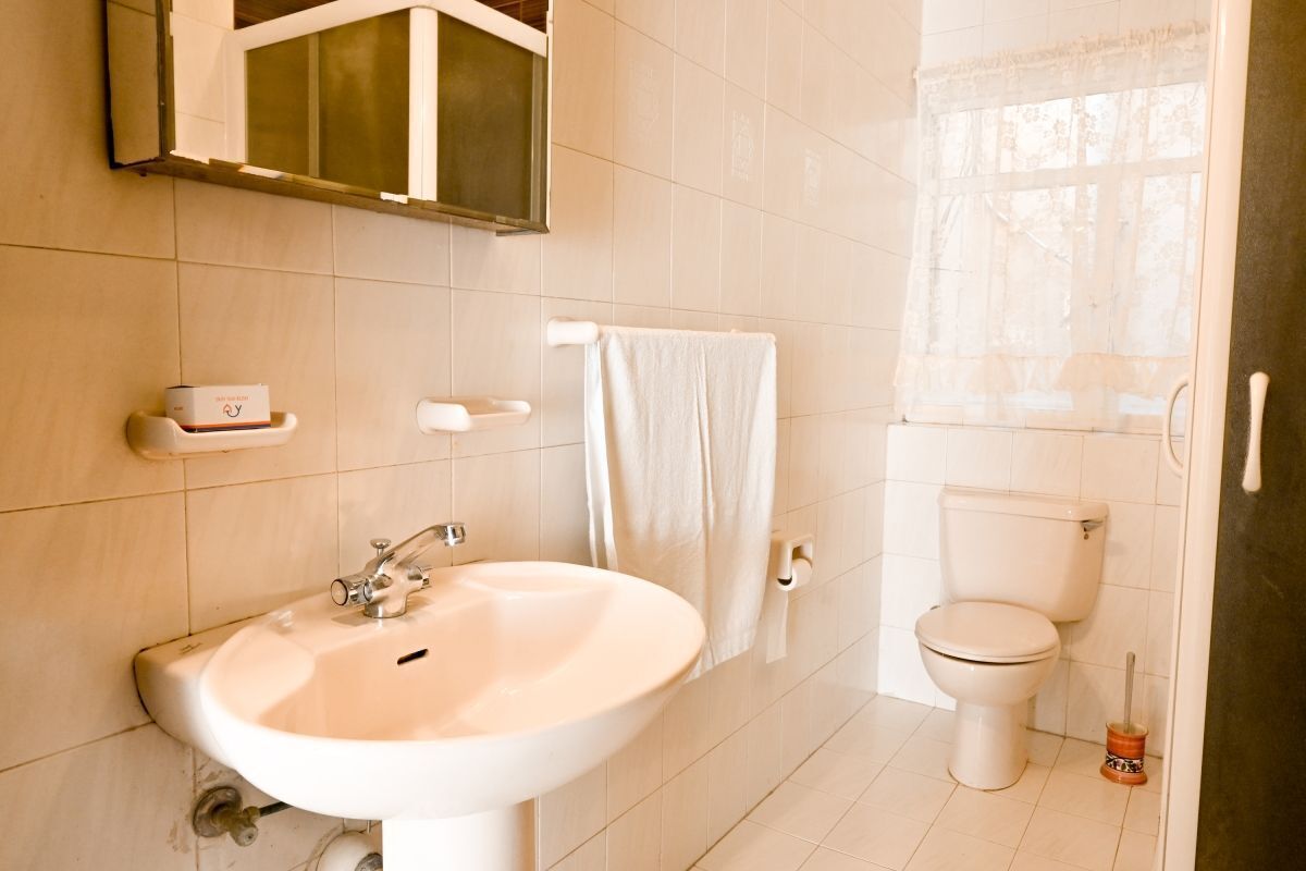A bathroom with a white sink, toilet, and a towel hanging on the wall.