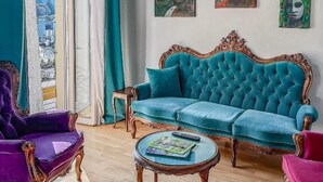 A living room with a teal sofa, purple armchairs, a wooden coffee table, and artwork on the wall. - Appartamento Splendore (Bellagio)