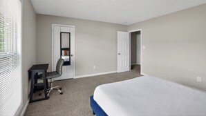 A bedroom with a bed, a desk, and two doors. - Spacious 2BR with 1.5 baths, modern living (Riverdale)