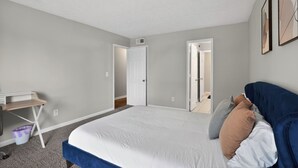Ein Schlafzimmer mit einem Bett, einem Schreibtisch und einer Tür zu einem weiteren Raum.