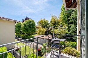 A balcony with a metal railing, a table, and a bench. - Holiday Home 'Ezia' with Mountain View and Small Private Garden (Porlezza)