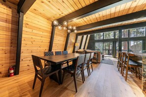 Ein Holzinterieur mit Esstisch, Stühlen, einem Feuerlöscher und großen Fenstern.