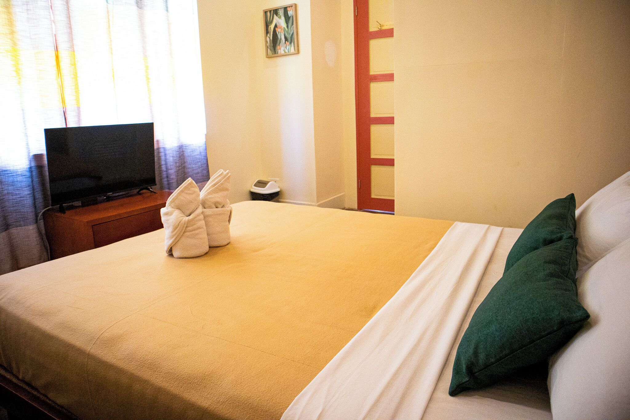 A hotel room with a bed, pillows, a TV, and a bedside table.