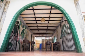 An arched entrance with a tiled floor, a hanging light fixture, and a view into a room with a door and a window. - Bethel Bed and Breakfast Bantayan (Bantayan)