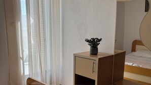 A bedroom with a bed, a bedside table with a plant, a mirror, and a wardrobe. - Cozy 1-bedroom apartment in fantastic Budva with AC (Budva)