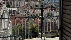 A balcony with a view of a cityscape, including buildings and mountains. - Cozy 1-bedroom apartment in fantastic Budva with AC (Budva)