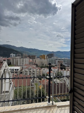 Een balkon met uitzicht op een stadsgezicht, inclusief gebouwen en bergen.