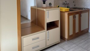 A modern kitchen with wooden cabinets, a countertop, and a sink. - Cozy 1-bedroom apartment in fantastic Budva with AC (Budva)