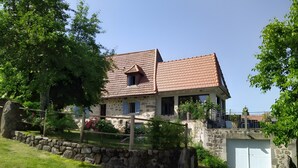 A stone house with a tiled roof, a stone wall, and a garage. - Cottage (4/7 guests) with valley view in the heart of the volcano park (Jou-sous-Monjou)