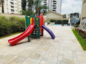 Um parquinho com escorregadores e área de piscina em um bairro residencial.