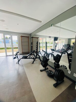 Une salle de sport équipée de matériel d’exercice, dotée d’un grand miroir et offrant une vue sur l’extérieur.