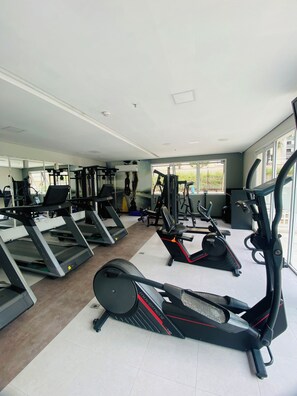 Une salle de sport équipée de tapis de course, de vélos elliptiques et de matériel de musculation.