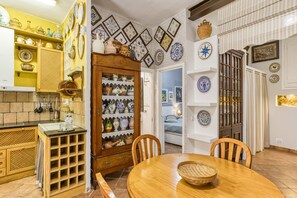 Een keuken met een houten tafel, stoelen en een kast met servies.
