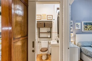 Een kleine badkamer met een toilet, planken en een wastafel.