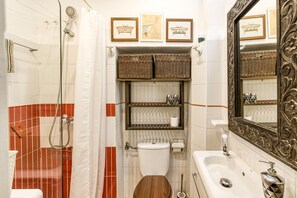A bathroom with a shower, toilet, sink, and decorative baskets.