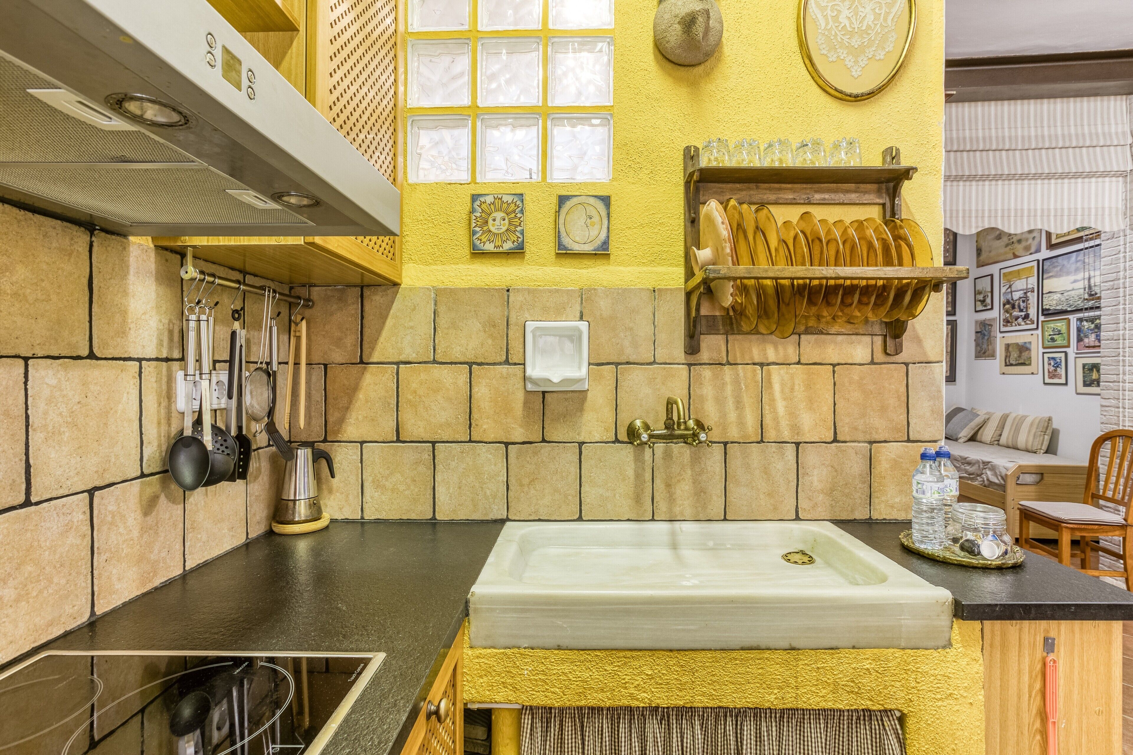 A kitchen with a large sink, a coffee machine, and a shelf with plates.