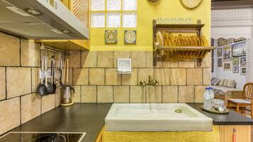 A kitchen with a large sink, a coffee machine, and a shelf with plates.