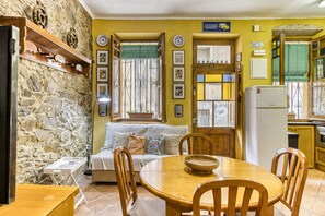A cozy living area with a stone wall, a wooden dining table, and a sofa.