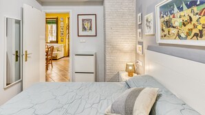 A bedroom with a bed, a nightstand, a lamp, and a painting on the wall.