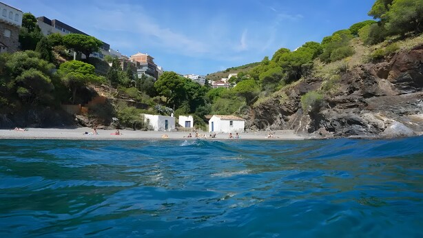 A coastal area with buildings, a beach, and rocky terrain.