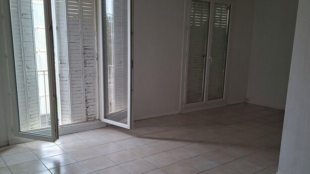 Ein Zimmer mit Fliesenboden, einer Schiebetür aus Glas und einer Tür mit Fenster.
