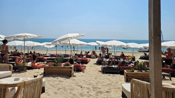Un caffè sulla spiaggia con posti a sedere all'aperto, ombrelloni e vista sul mare.