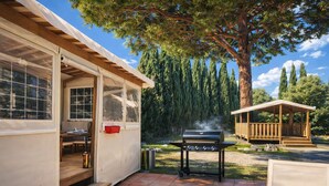Un’area esterna coperta con una griglia, panche di legno e un piccolo padiglione.
