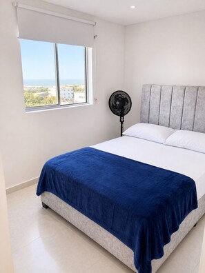 Ein Schlafzimmer mit einem Bett, einem Fenster mit Blick und zwei Deckenventilatoren.