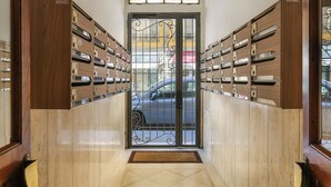 Un couloir avec une porte donnant sur un parking, de part et d’autre de laquelle se trouvent des casiers en bois.