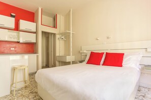 A hotel room with a bed, a small stool, a wardrobe, and a bathroom door. - The Red Loft in Ponte Vecchio (Florence)